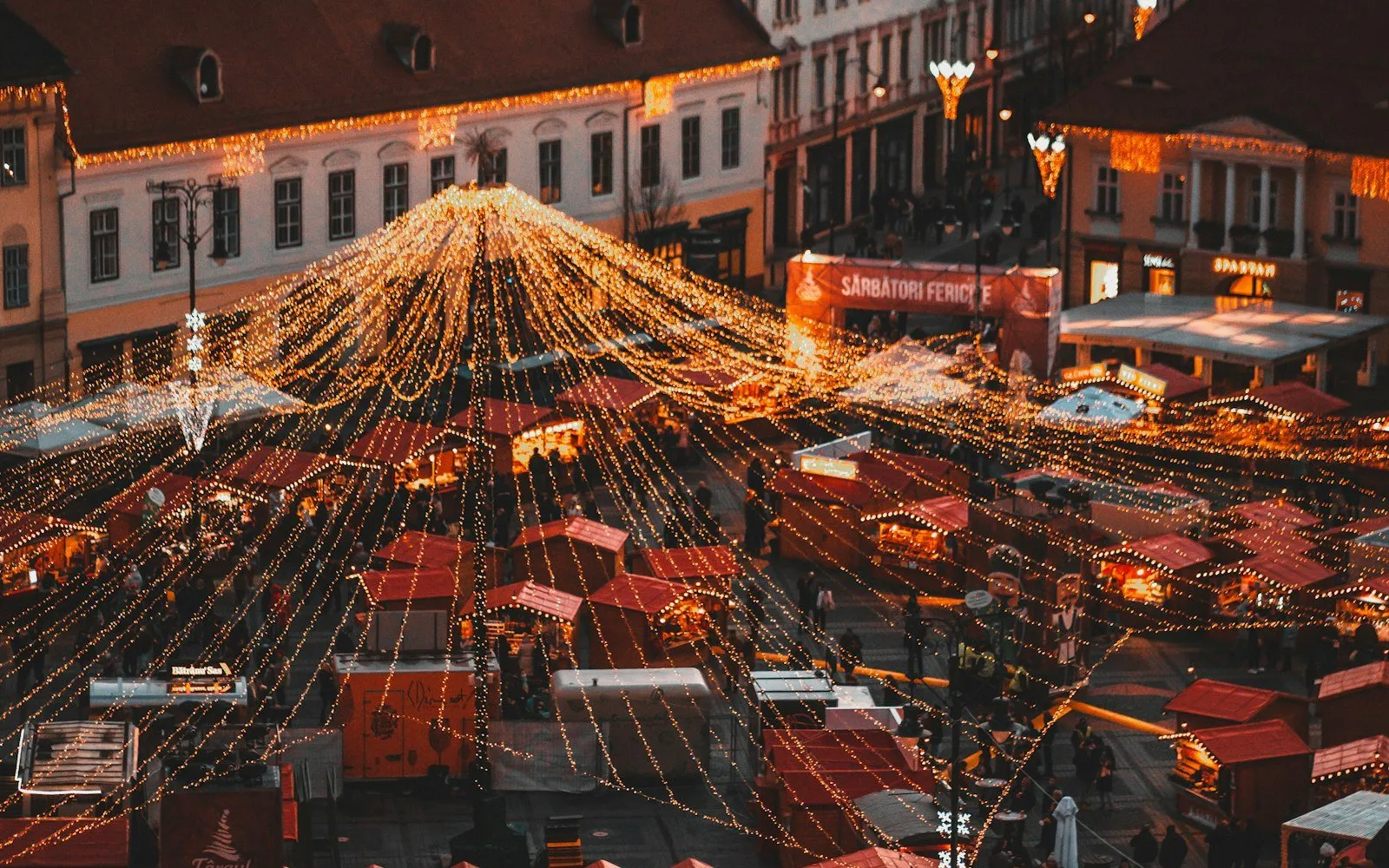 A Christmas market with lit stalls seen from above at night